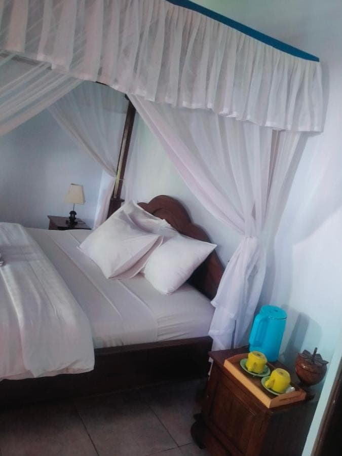 a bedroom with a white bed with a canopy at Coral Bay Bungalows Amed Bali in Amed