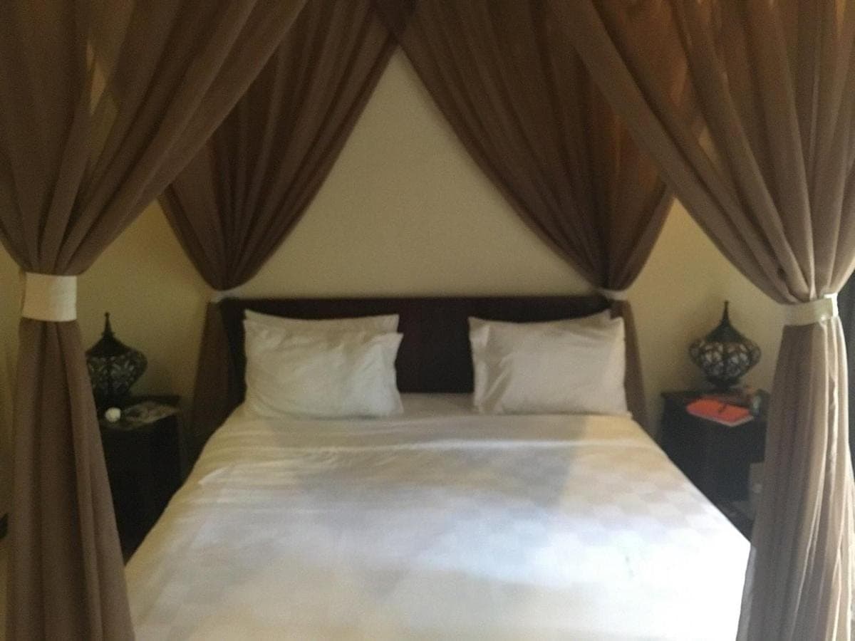 a bedroom with a canopy bed with white pillows at Pekak Mangku Guest House in Ubud
