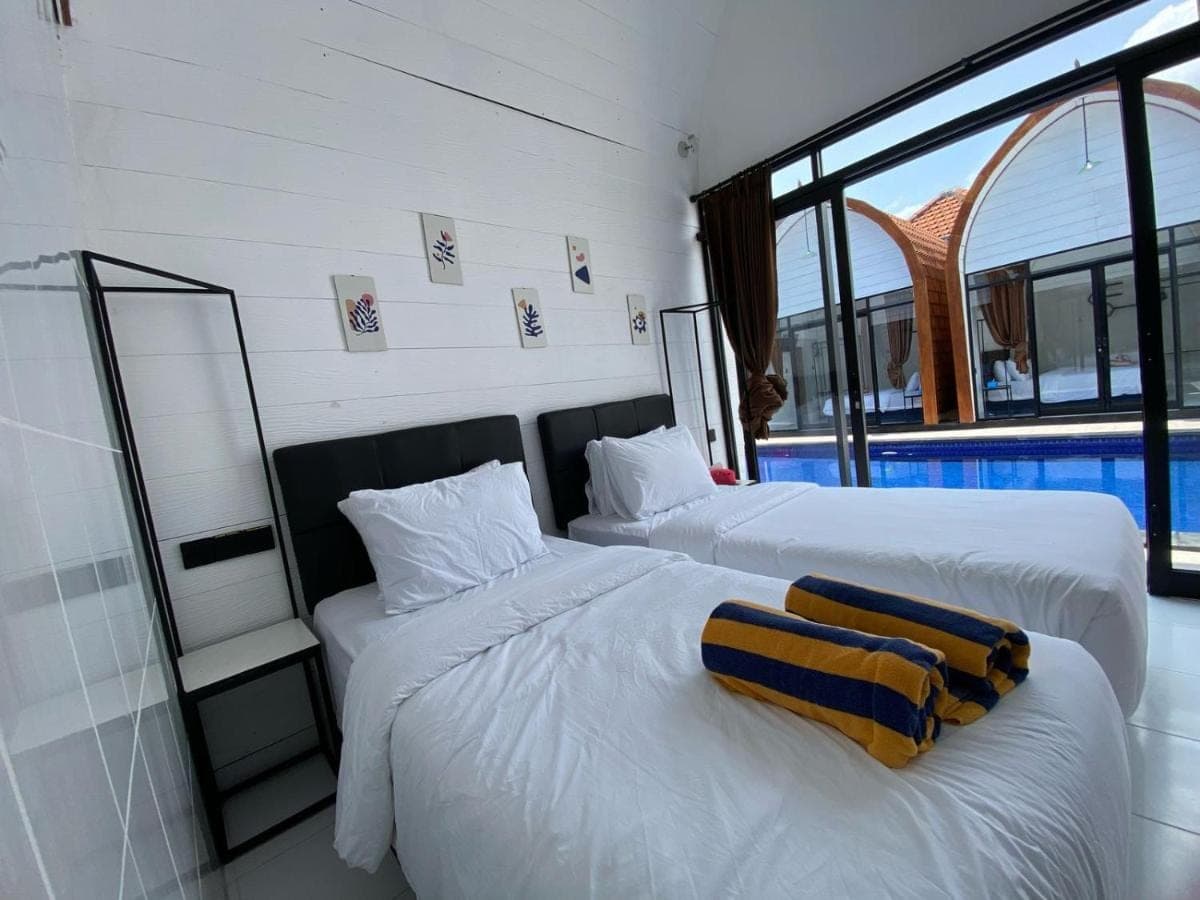a bedroom with two beds and a window at HK Villa Family in Seminyak
