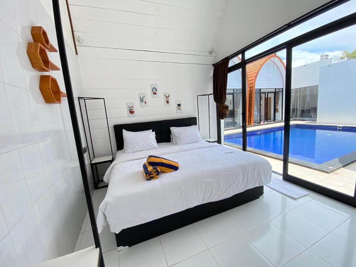 a bedroom with a bed and a swimming pool at HK Villa Family in Seminyak