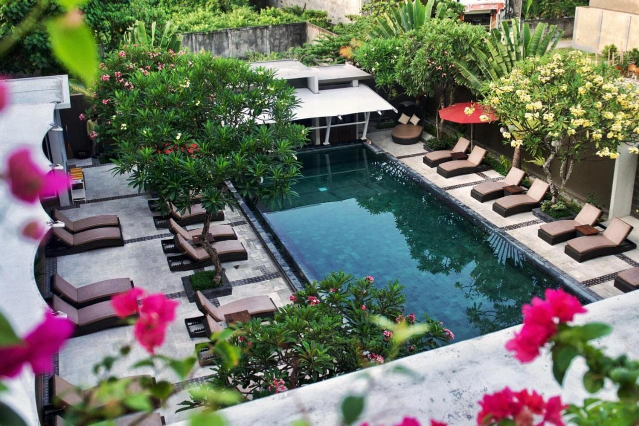 an overhead view of a swimming pool with chairs and flowers at The Kana Kuta Hotel in Kuta