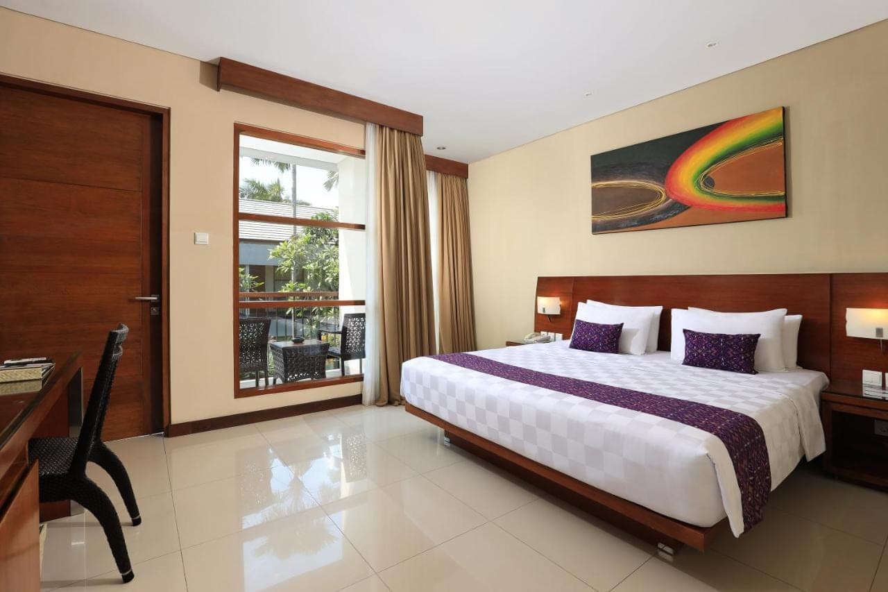 a bedroom with a bed and a desk and a window at Amadea Resort & Villas Seminyak Bali in Seminyak