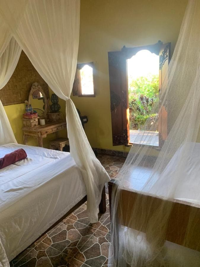 a bedroom with a bed with white mosquito netting at Jana's Homestay in Sidemen