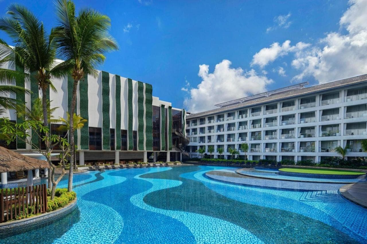 a hotel with a swimming pool in front of two buildings at The Stones Hotel - Legian Bali in Kuta