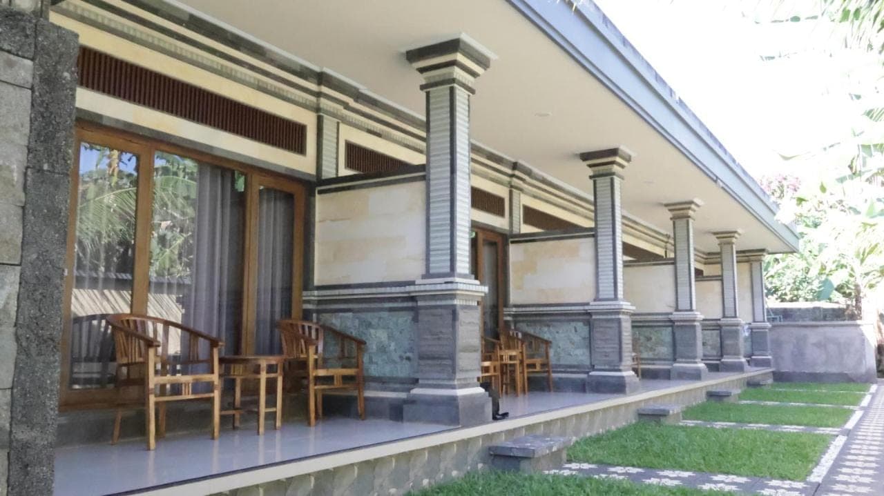 a house with chairs and tables on the porch at Nick Homestay Bali in Uluwatu