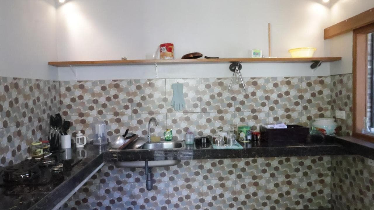 a kitchen with a sink and a tiled wall at Nick Homestay Bali in Uluwatu