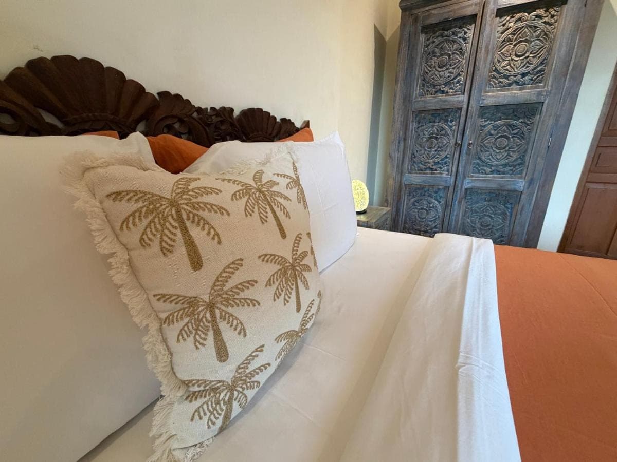a bed with a pillow with palm trees on it at Private Apartment 6505 at the Jayakarta Residence in Seminyak