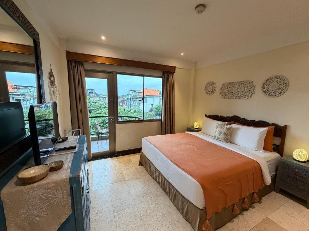 a bedroom with a bed and a tv and a window at Private Apartment 6505 at the Jayakarta Residence in Seminyak