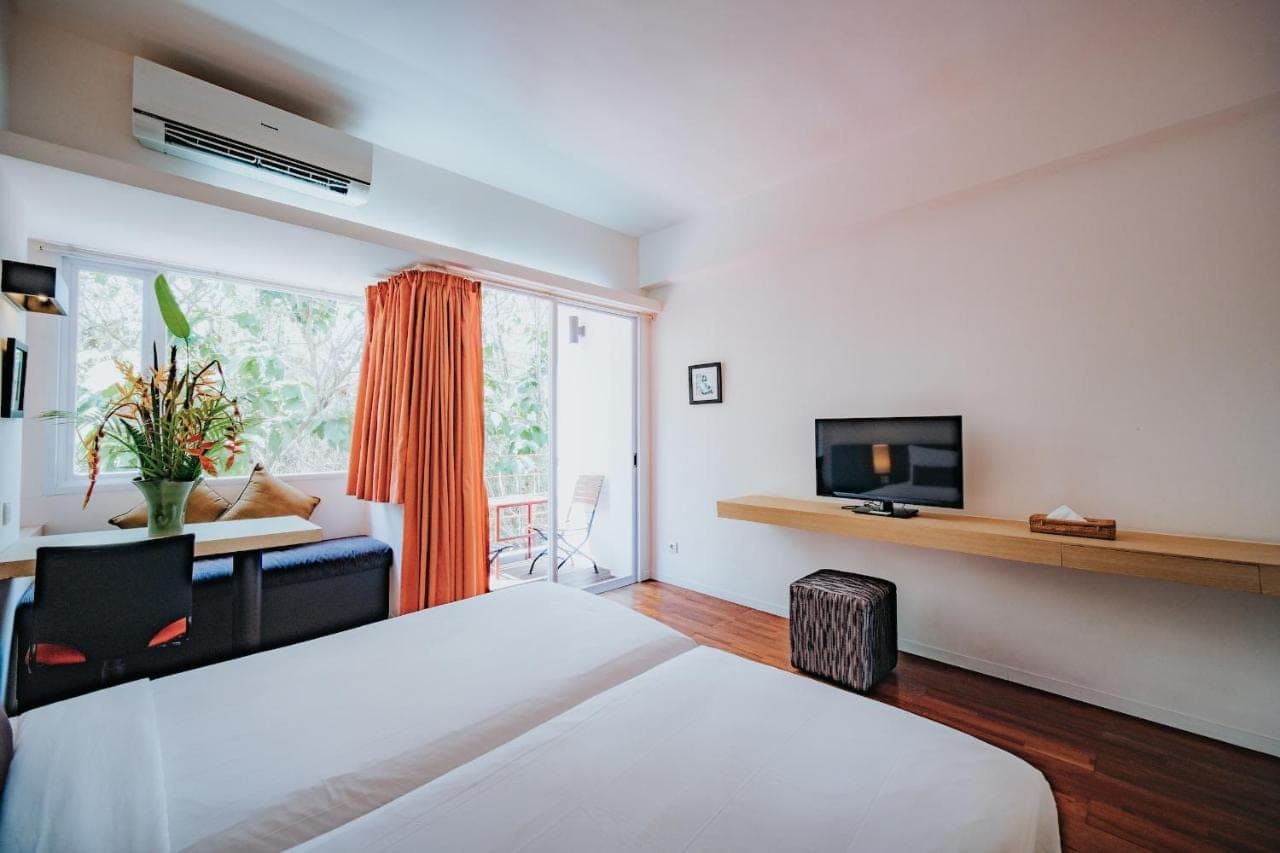 a bedroom with a bed and a desk and a tv at Allia Residence in Nusa Dua