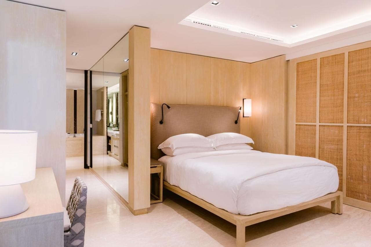a bedroom with a large white bed and a mirror at COMO Canggu in Canggu