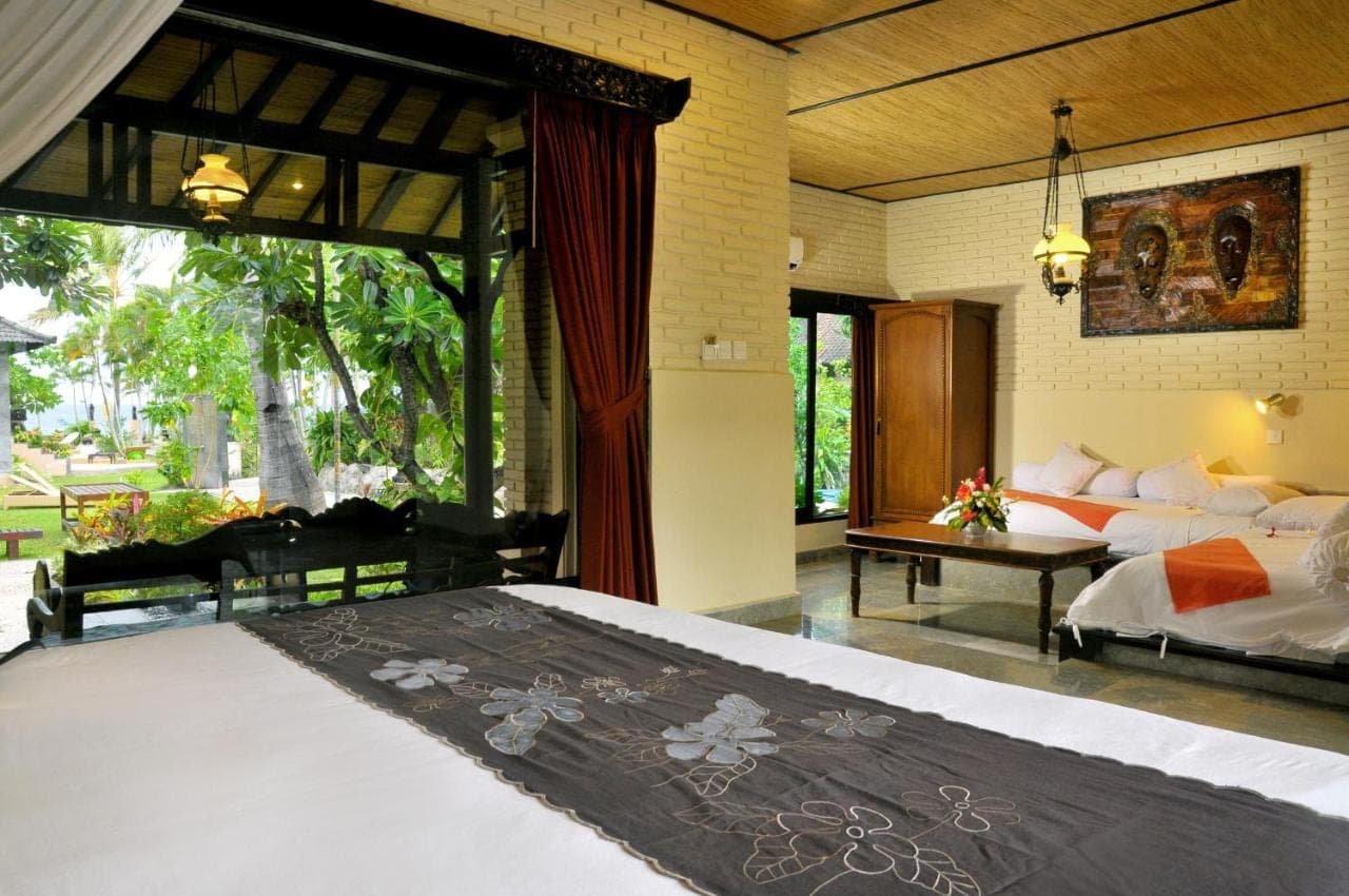 a bedroom with a large bed and a large window at Hidden Paradise Cottages in Amed