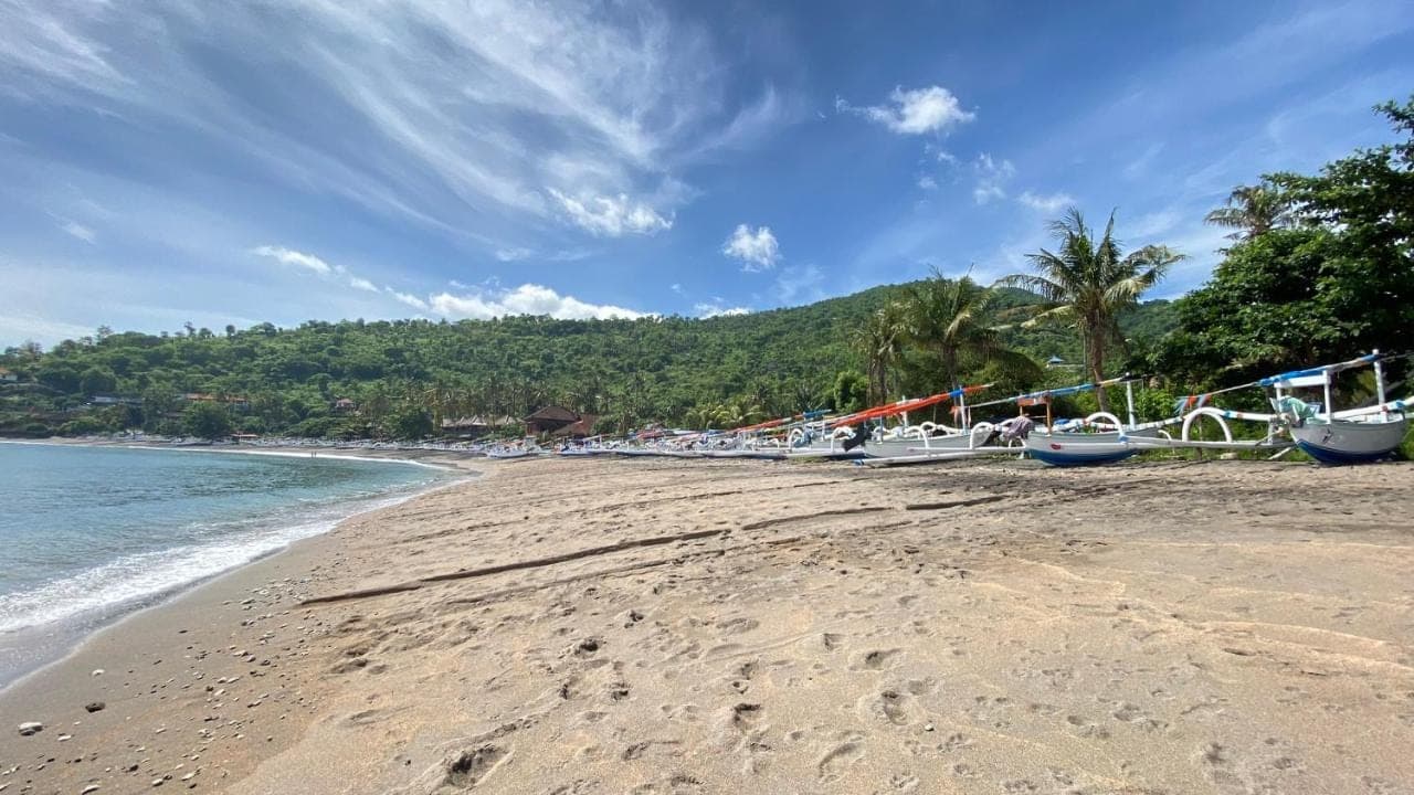 a beach with boats on the sand and the water at Hidden Paradise Cottages in Amed