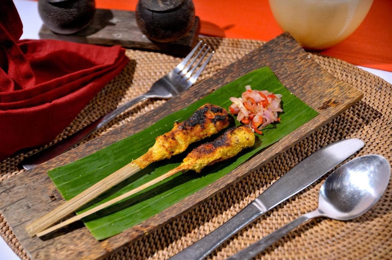 a plate of food on a wooden board with chopsticks at Hidden Paradise Cottages in Amed