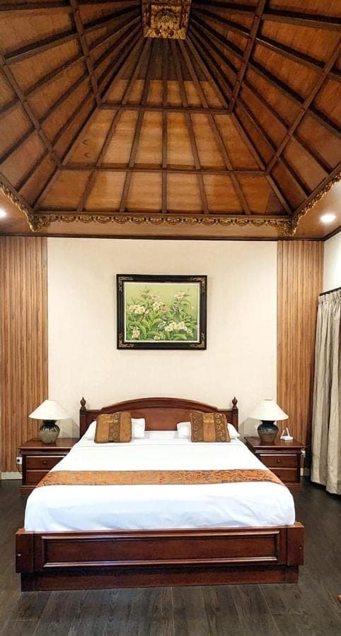 a bedroom with a large bed with a wooden ceiling at Stana Puri Gopa Hotel in Sanur