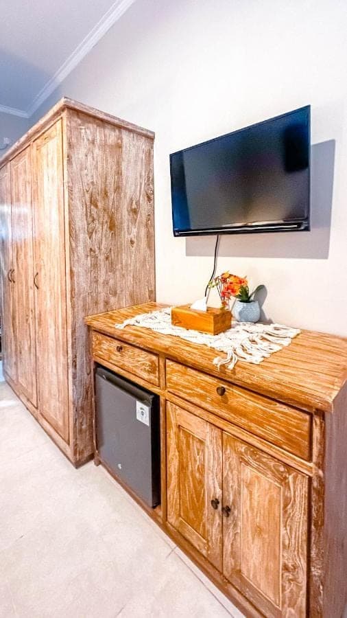 a large wooden cabinet with a television on a wall at Adhi Homestay in Nusa Dua