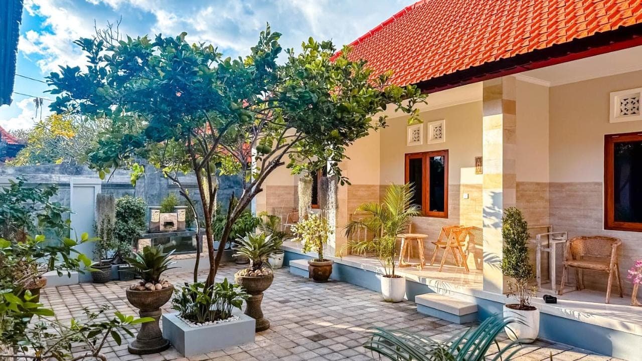 a house with a courtyard with trees and plants at Adhi Homestay in Nusa Dua