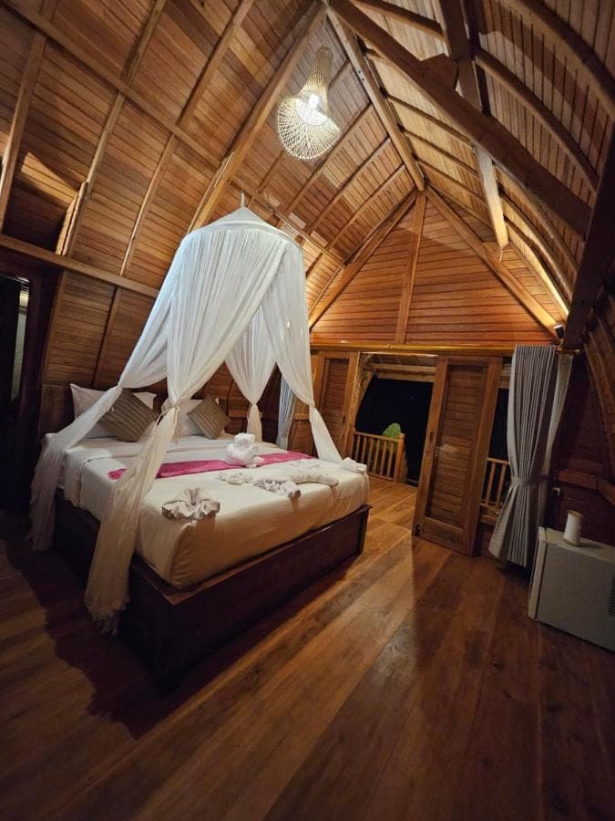 a bedroom with a bed with a mosquito net at Kubu Dangin Ogang Guest House in Sidemen