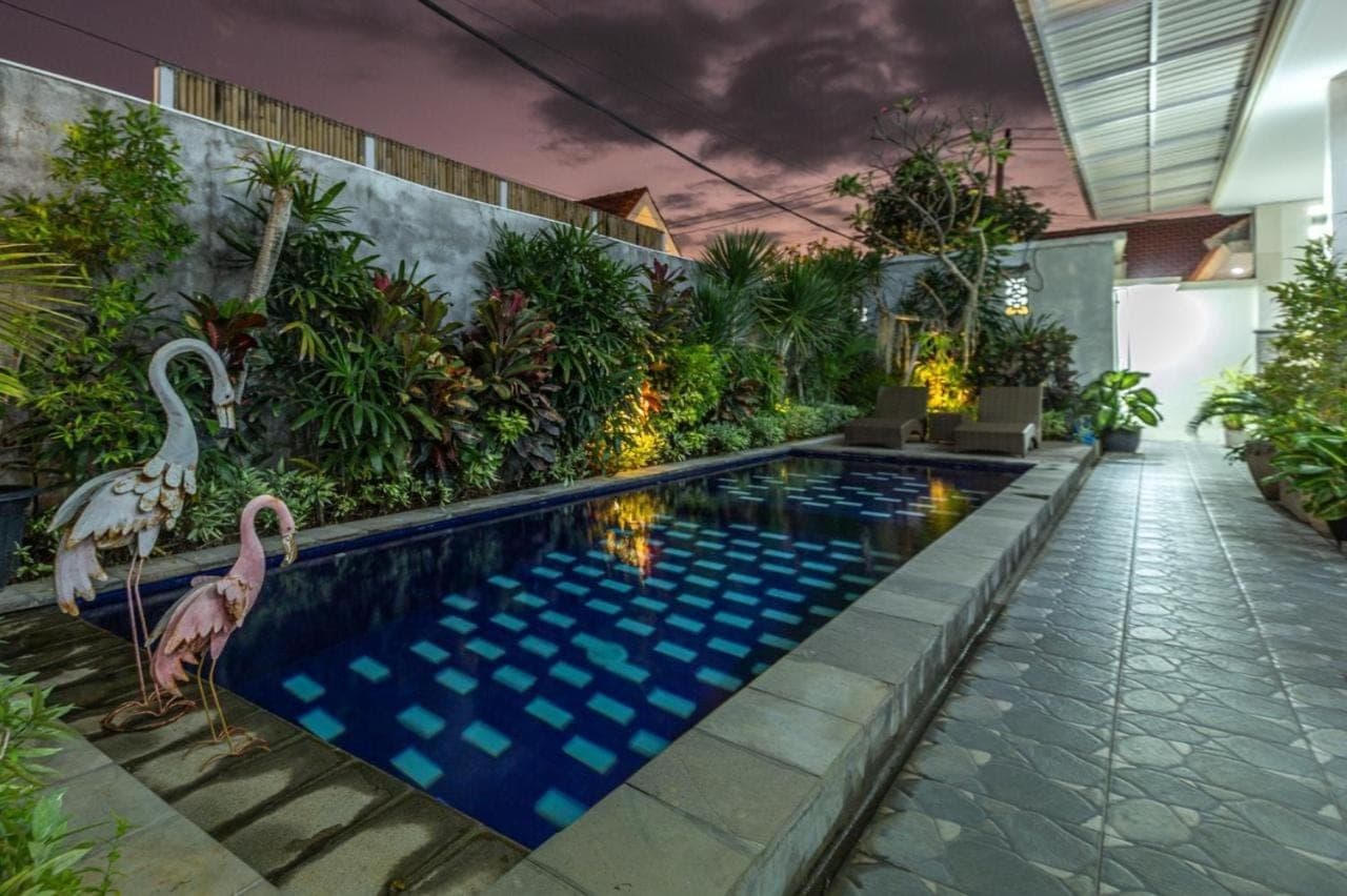 two flamingos standing by a swimming pool in a building at Kubu Ramah Suite Canggu in Canggu