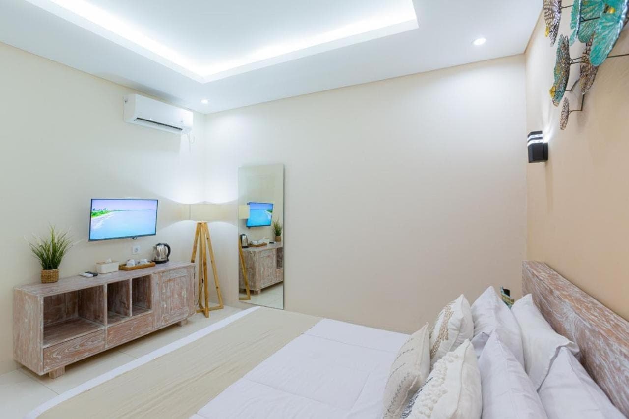 a bedroom with a bed and a tv on a wall at Kubu Ramah Suite Canggu in Canggu