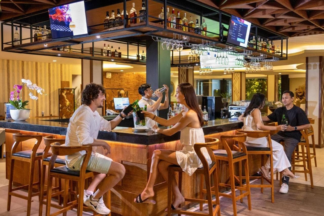 a group of people sitting at a bar at Taksu Sanur Hotel in Sanur