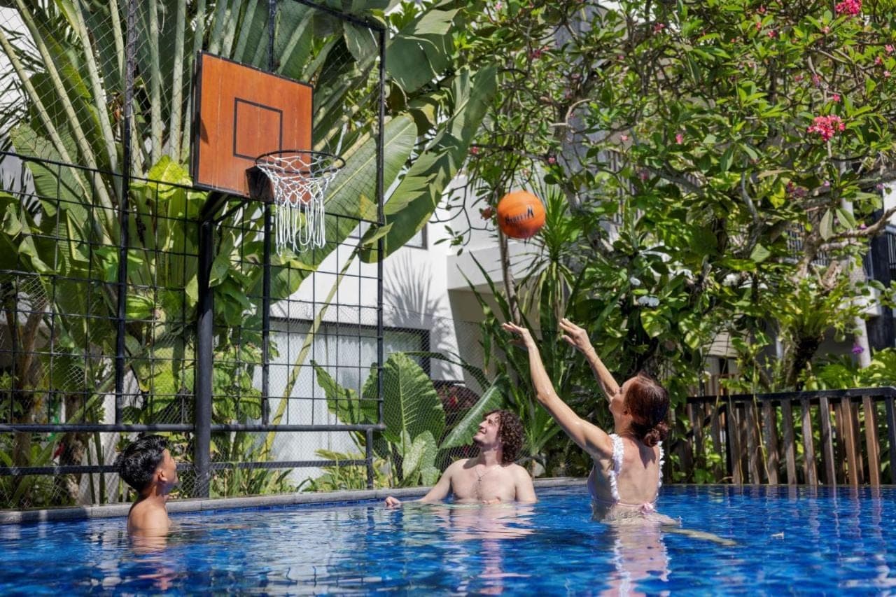 three children playing basketball in a swimming pool at Taksu Sanur Hotel in Sanur