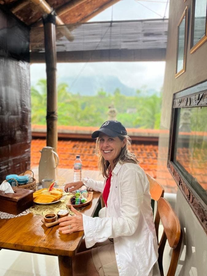a woman sitting at a table with a plate of food at Wayan Bola Homestay in Sidemen