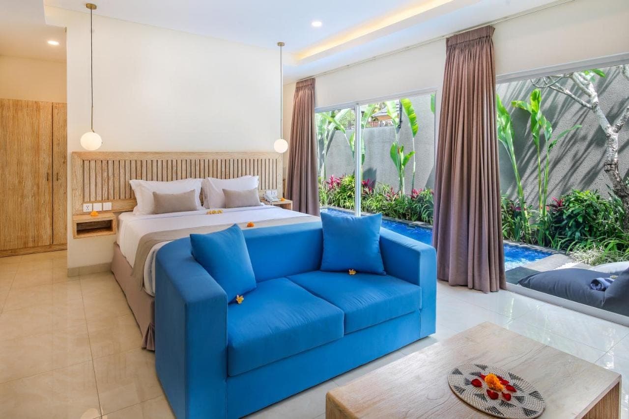 a bedroom with a bed and a blue couch at Le Cielo Romantic Villas by Maviba in Seminyak