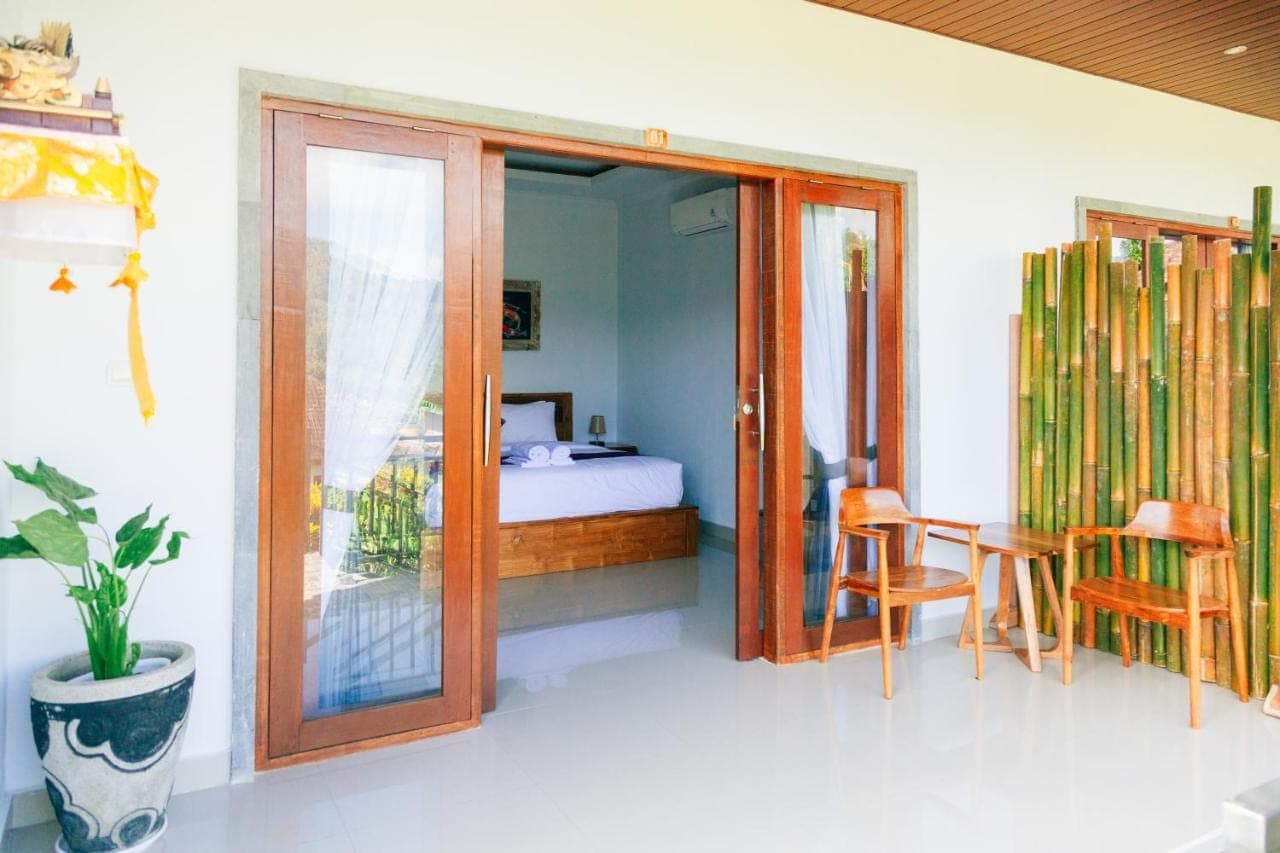 a room with a bed and a table and chairs at Anantalla Homestay in Sidemen