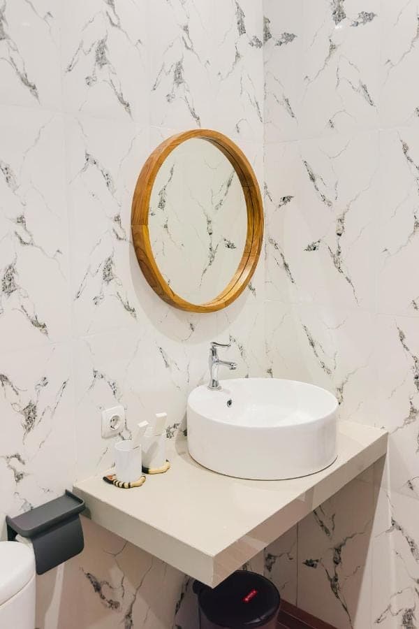 a white bathroom with a sink and a mirror at Anantalla Homestay in Sidemen