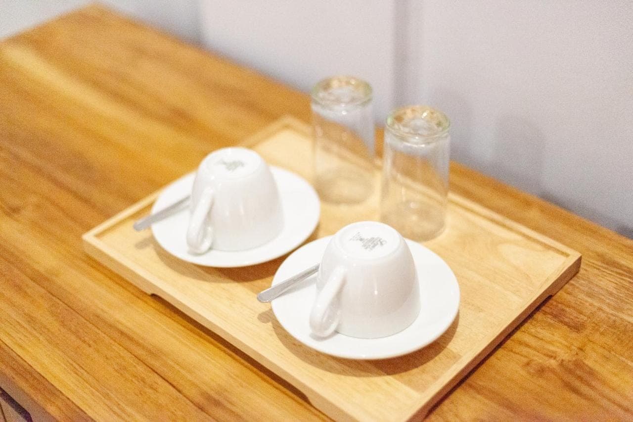 two white dishes on a wooden tray with glasses at Anantalla Homestay in Sidemen