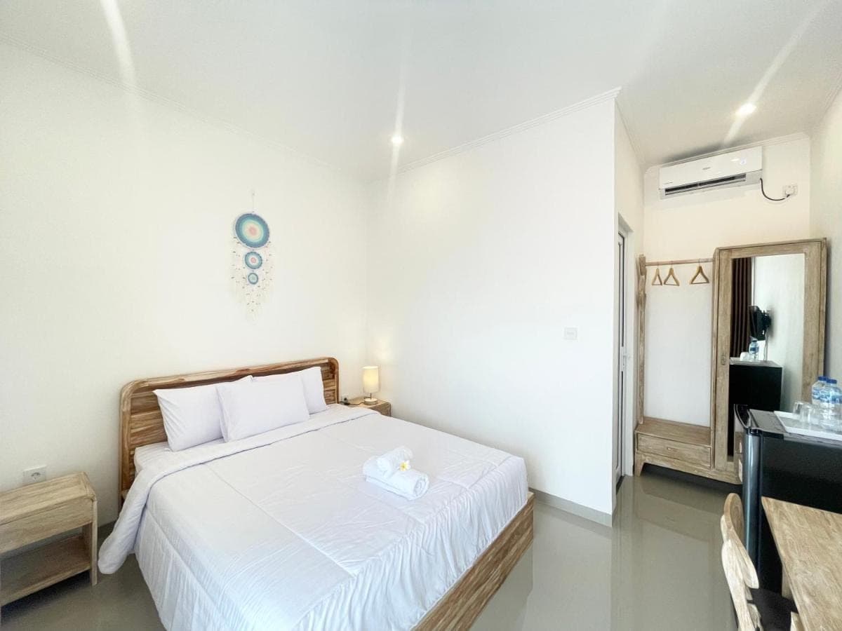 a bedroom with a white bed and a mirror at Umah Wayan Sanur in Sanur