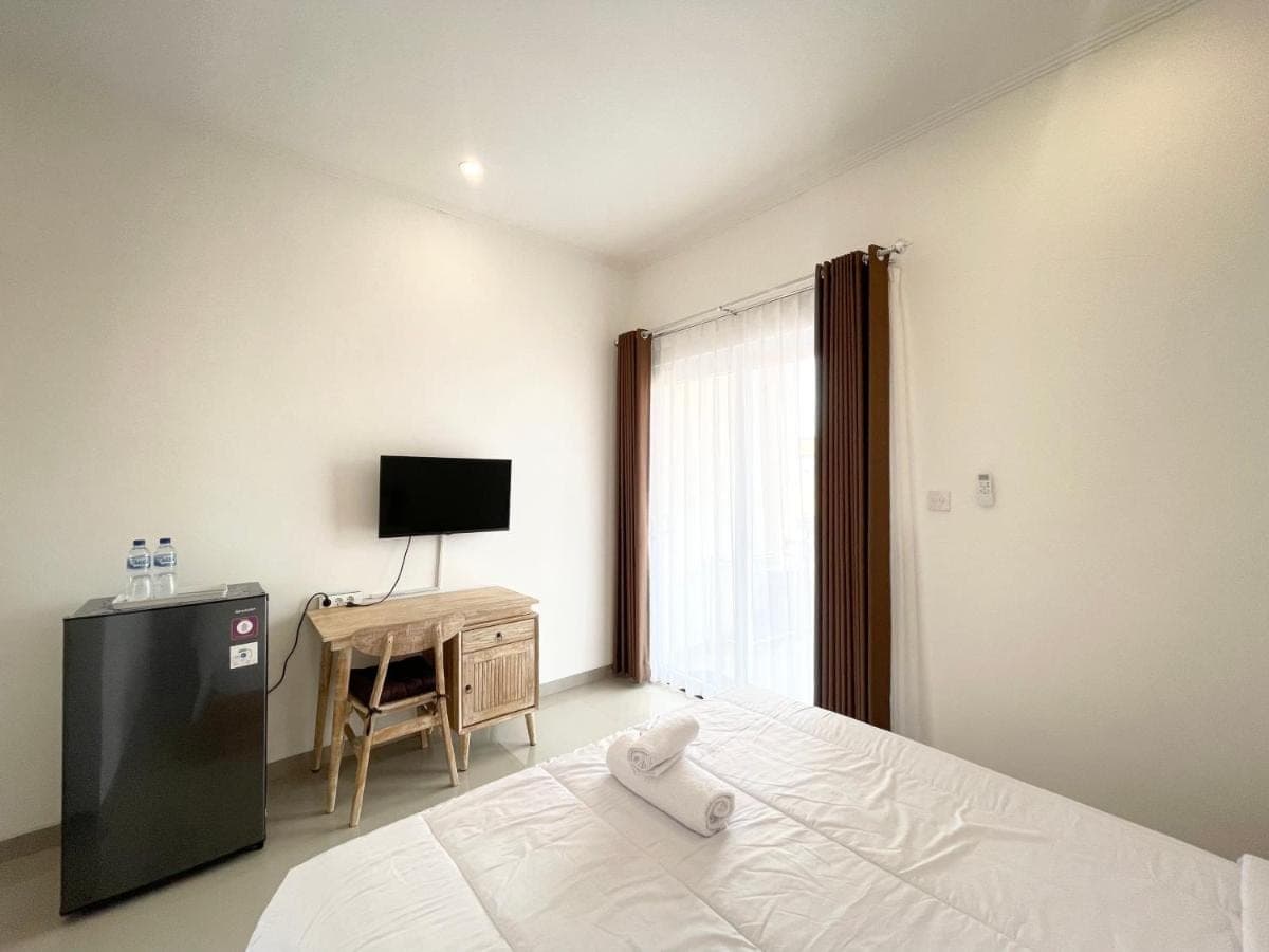 a bedroom with a bed with a television and a desk at Umah Wayan Sanur in Sanur