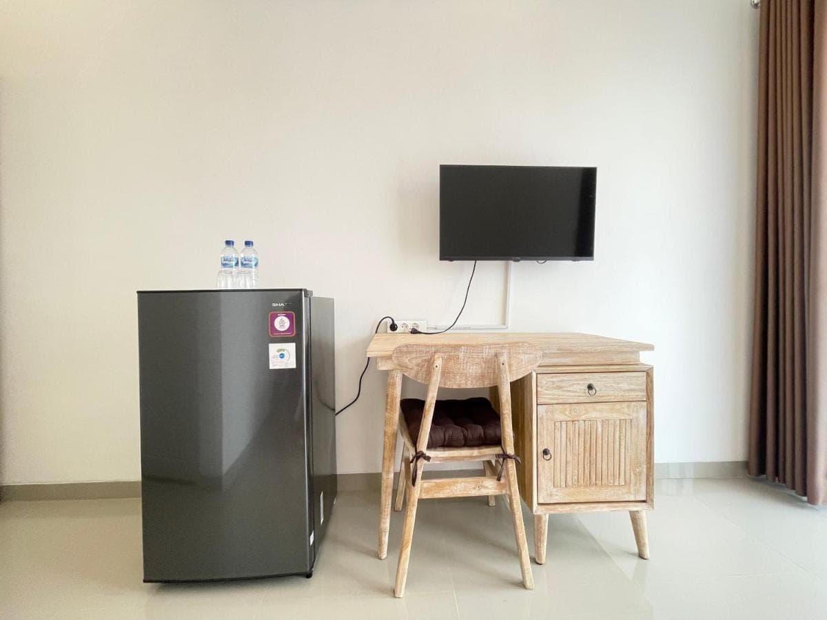 a black refrigerator next to a table with a television at Umah Wayan Sanur in Sanur