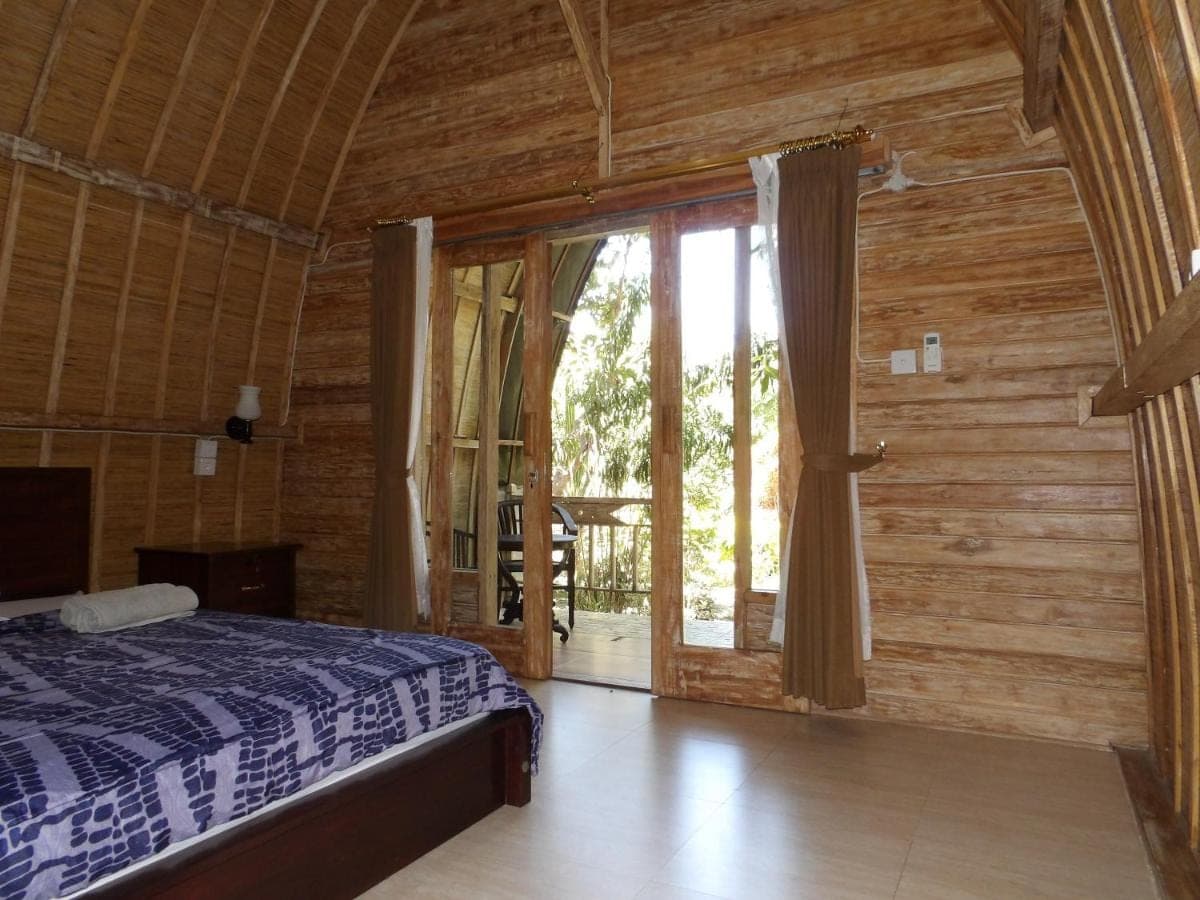 a bedroom with a bed and a sliding glass door at Lala Home Stay in Nusa Dua