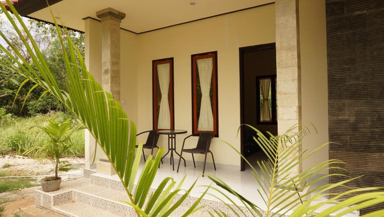 a patio with two chairs and a table on a house at Lala Home Stay in Nusa Dua