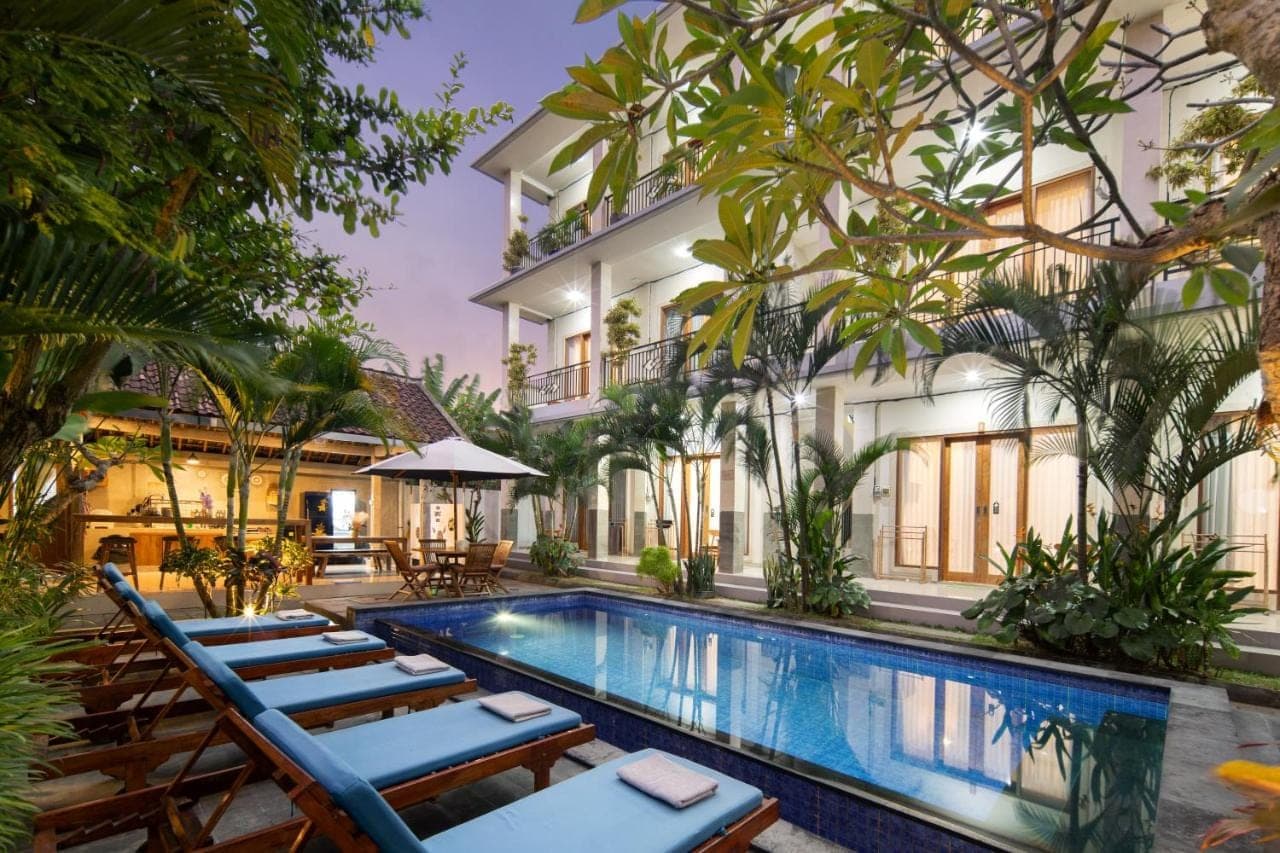 a resort pool with lounge chairs and a building at Canggu Nadi 2 Guest House in Canggu