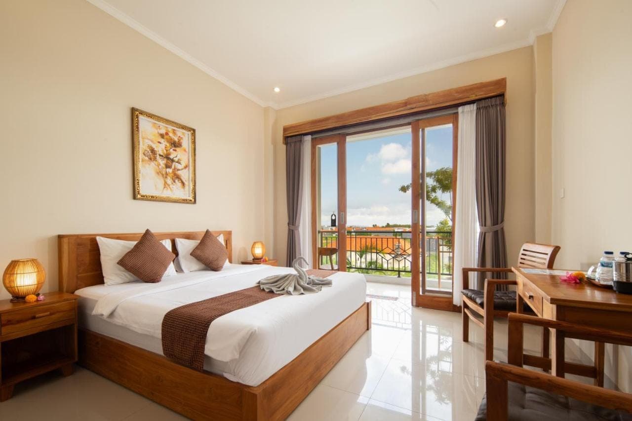 a bedroom with a bed and a large window at Canggu Nadi 2 Guest House in Canggu