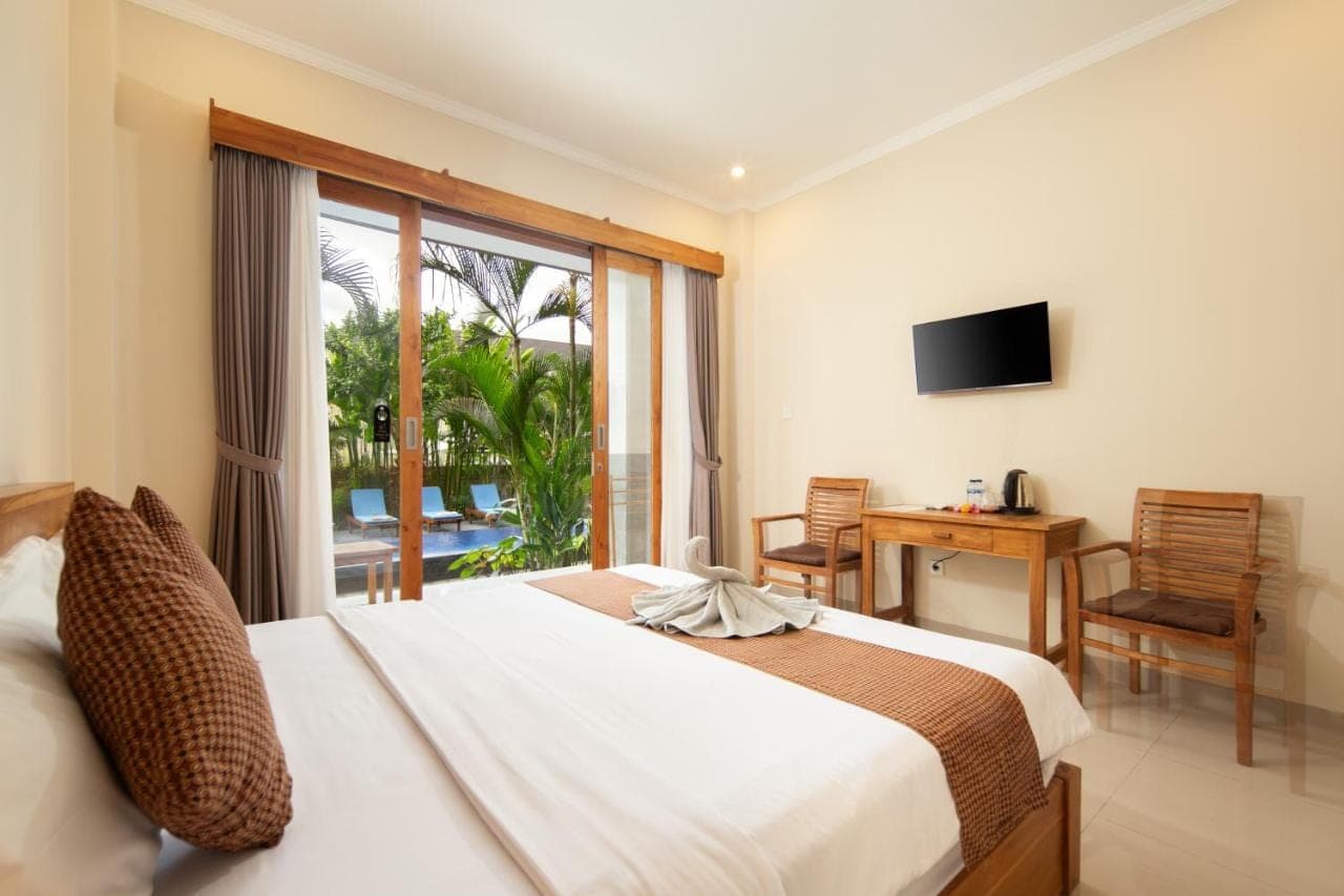 a bedroom with a bed and a window and a desk at Canggu Nadi 2 Guest House in Canggu