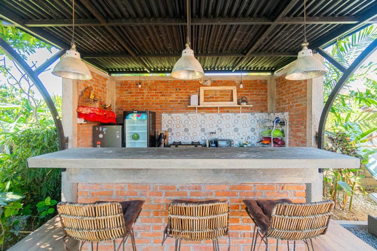 a patio with a bar with three chairs at Uluwatu Village House 2 by Bukit Vista in Uluwatu