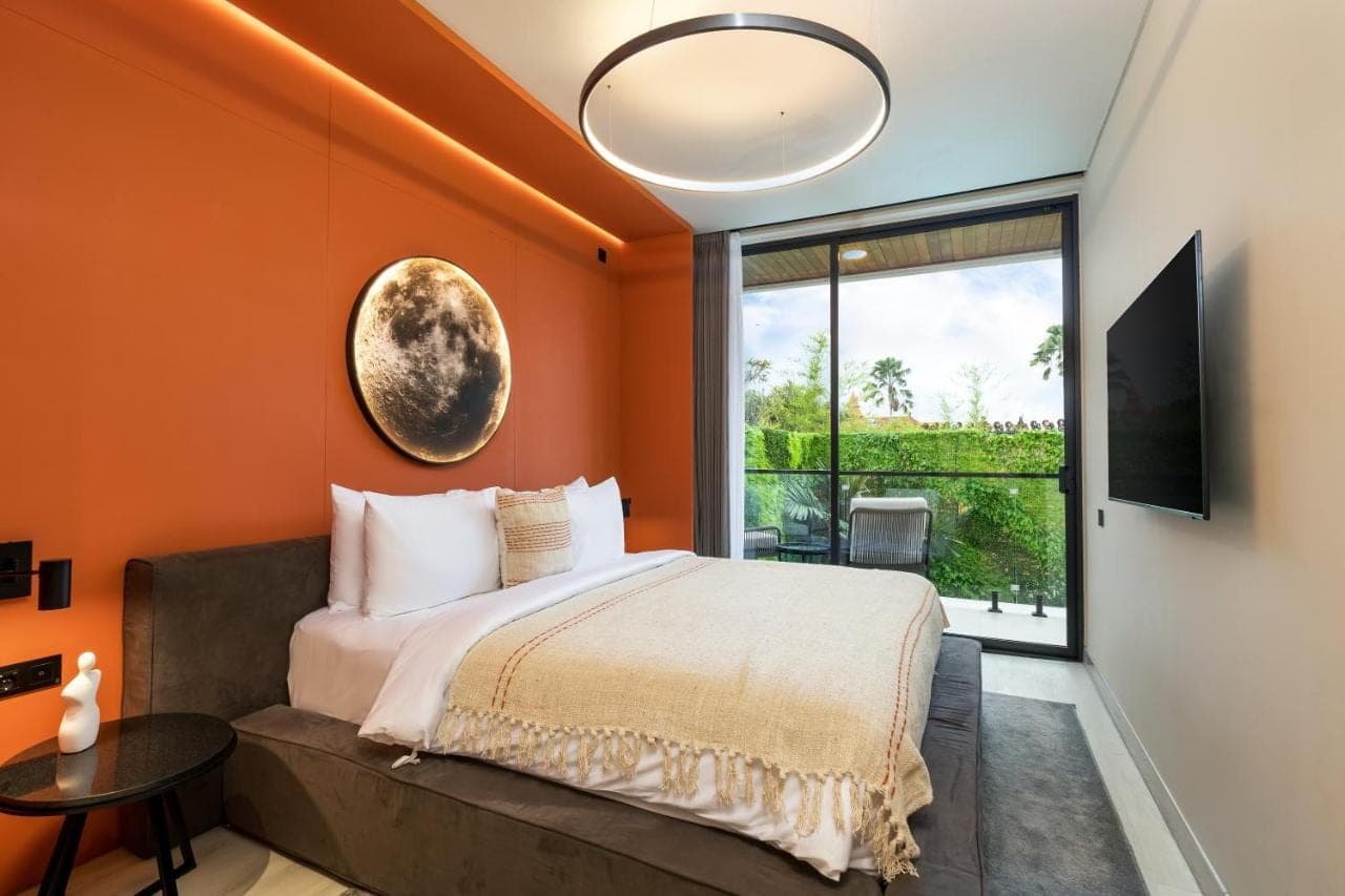 a bedroom with orange walls and a bed and a window at Alex Villas Complex N4 in Canggu