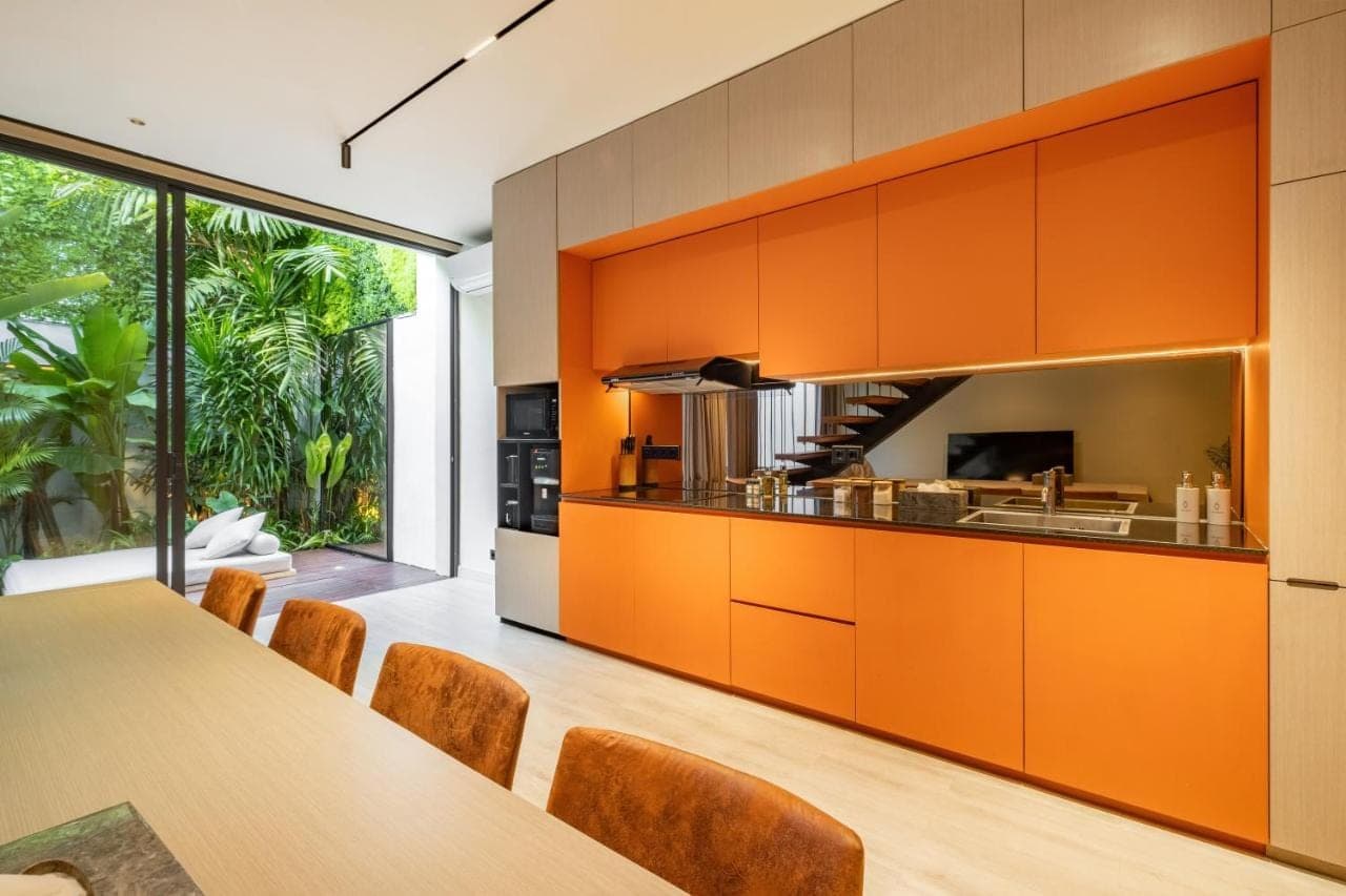 an orange kitchen with a table and chairs at Alex Villas Complex N4 in Canggu