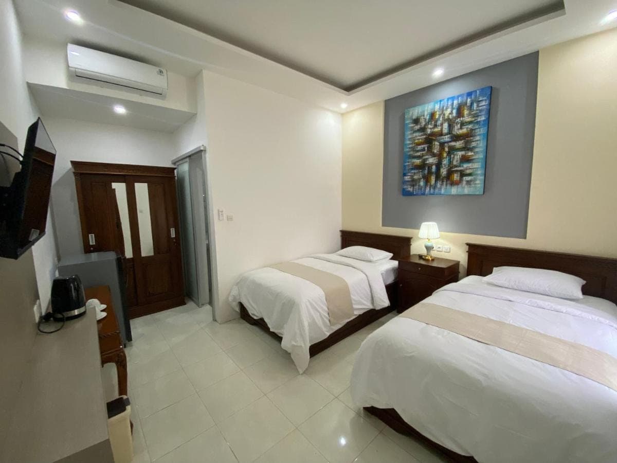 a hotel room with two beds and a tv at Bidadari Homestay Nusa Dua in Nusa Dua