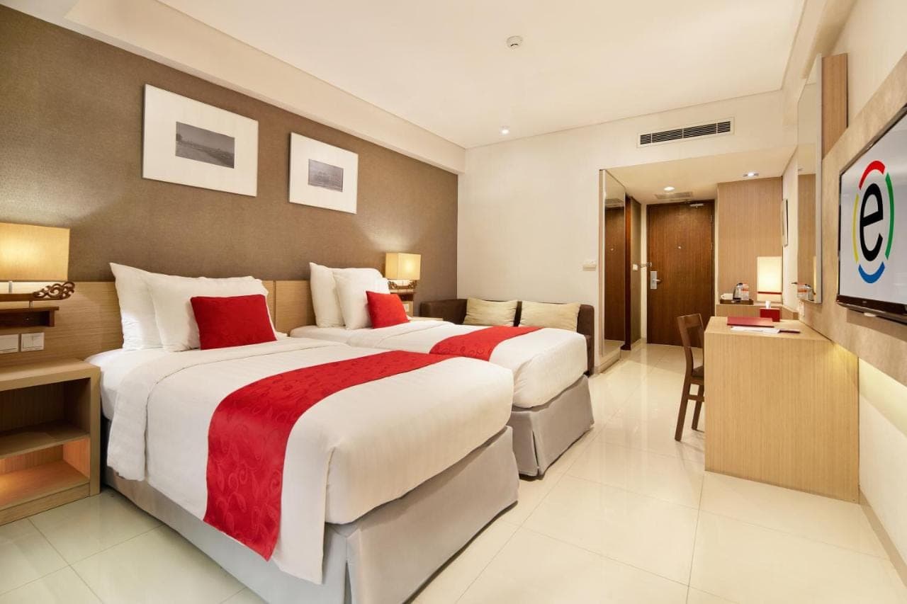 a hotel room with a large bed and a desk at Ramada Encore by Wyndham Seminyak Bali in Seminyak