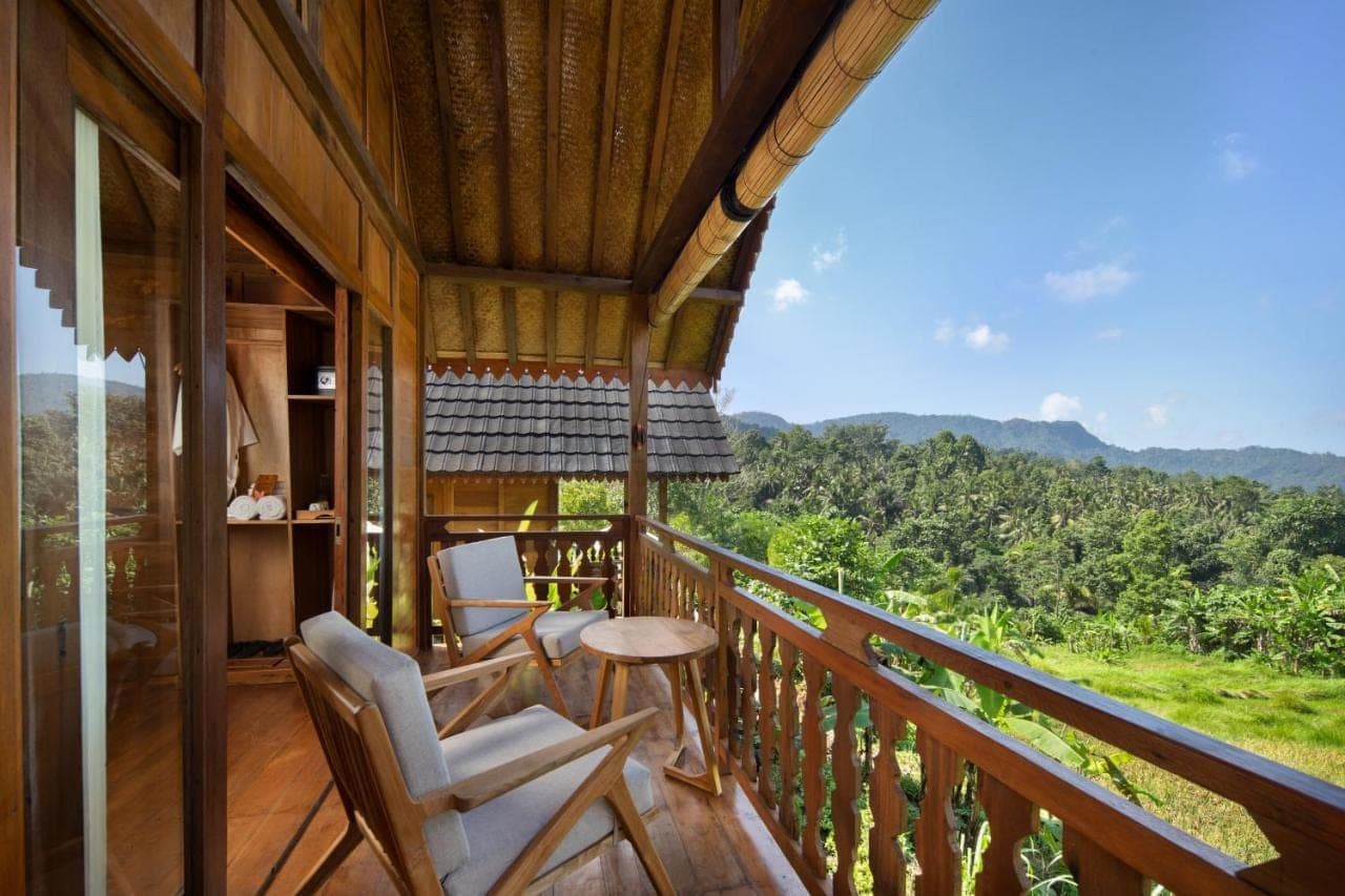 a balcony of a house with two chairs and a table at Devani Resort Sidemen in Sidemen
