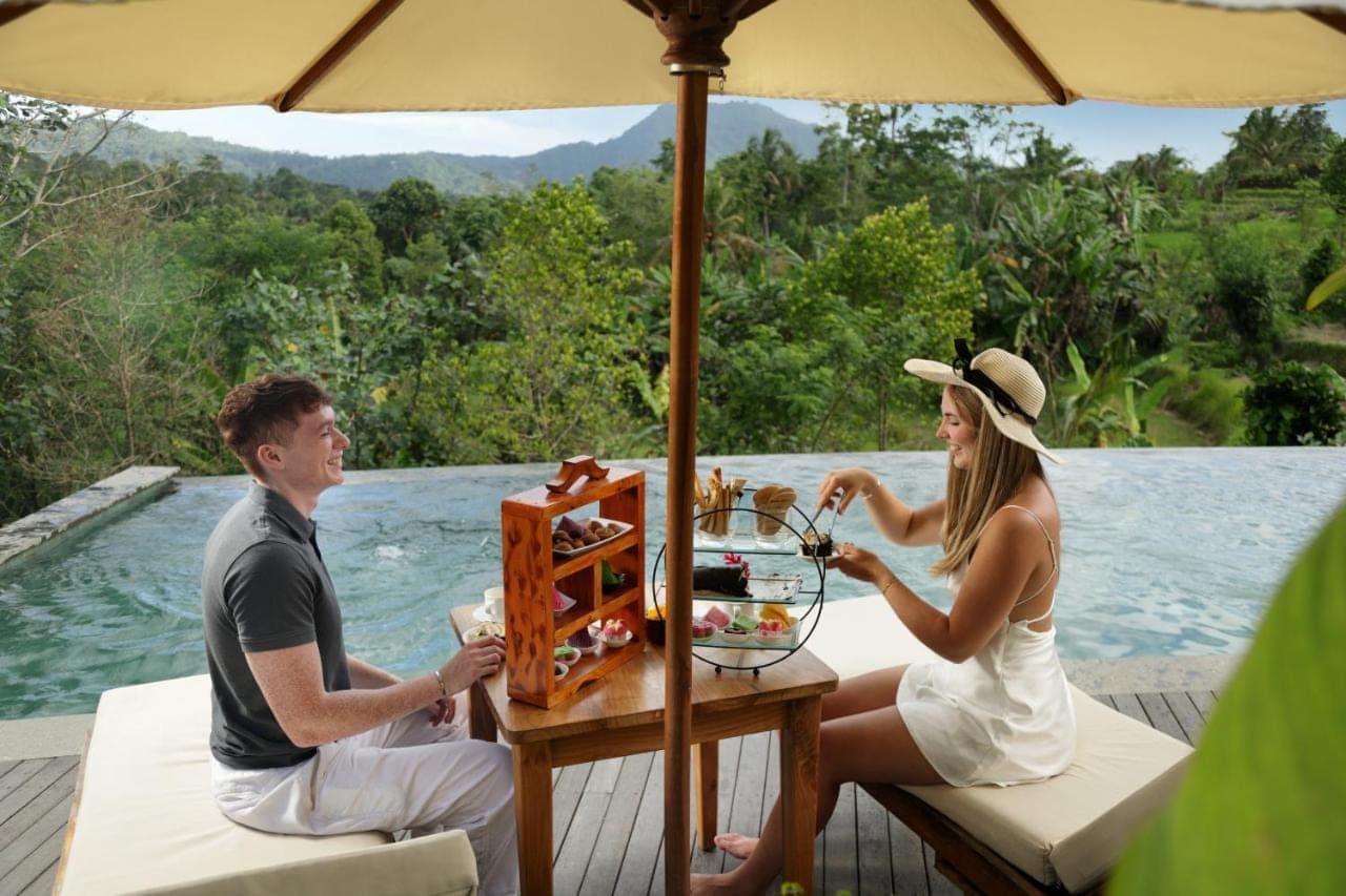 a man and woman sitting at a table under an umbrella at Devani Resort Sidemen in Sidemen