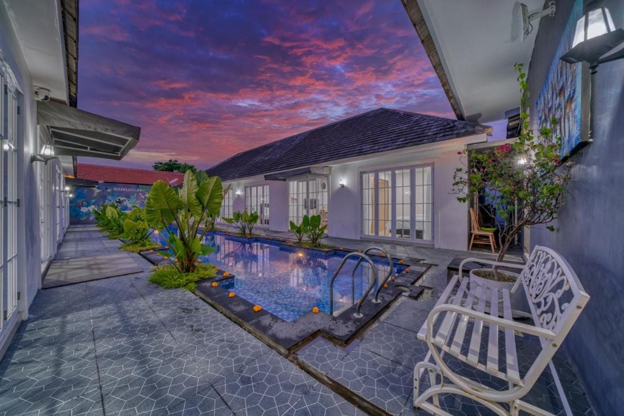 a villa with a swimming pool at dusk at 3BD Modern Apartment in Sanur with BBQ & huge shared pool in Sanur