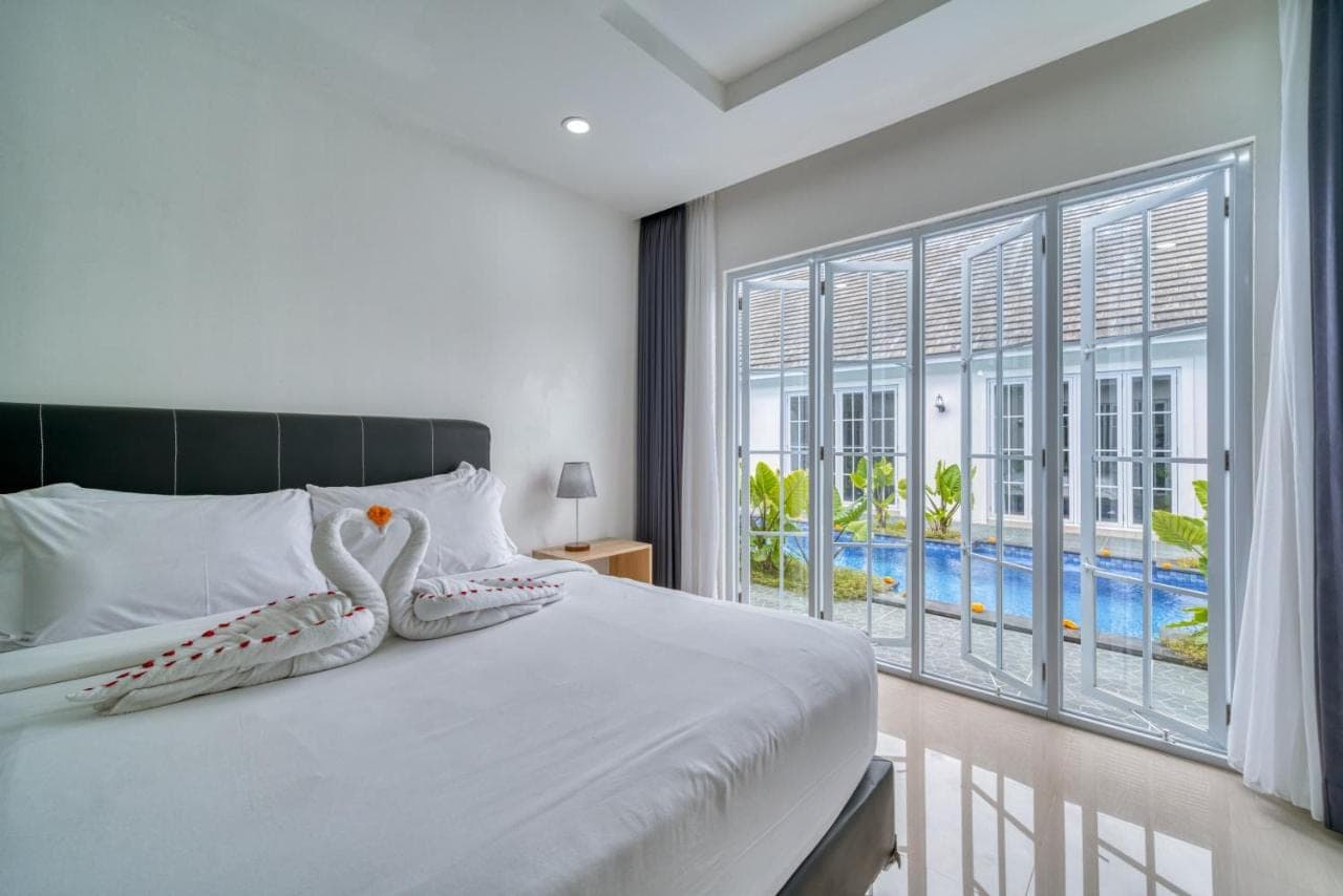 a bedroom with a bed and a large window at 3BD Modern Apartment in Sanur with BBQ & huge shared pool in Sanur