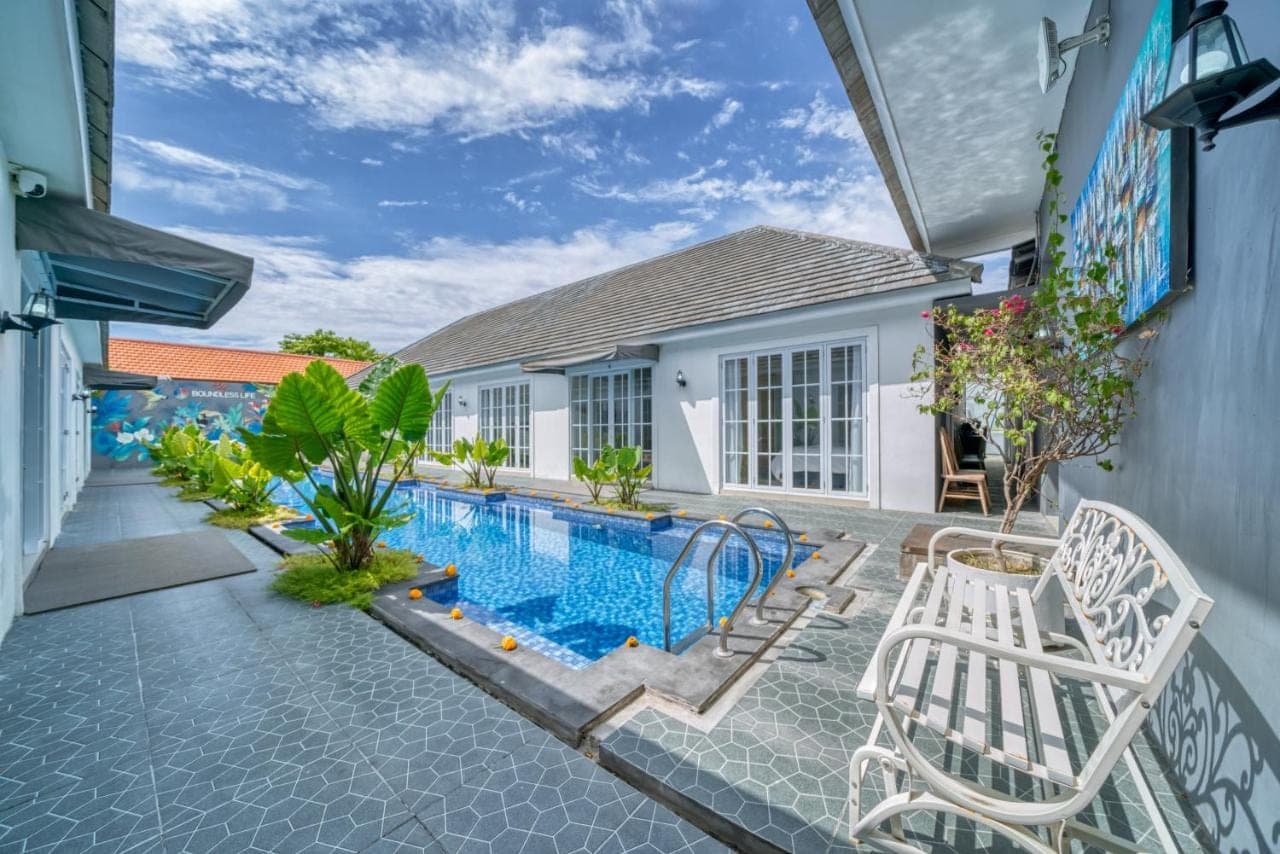 a swimming pool with two chairs next to a house at 3BD Modern Apartment in Sanur with BBQ & huge shared pool in Sanur