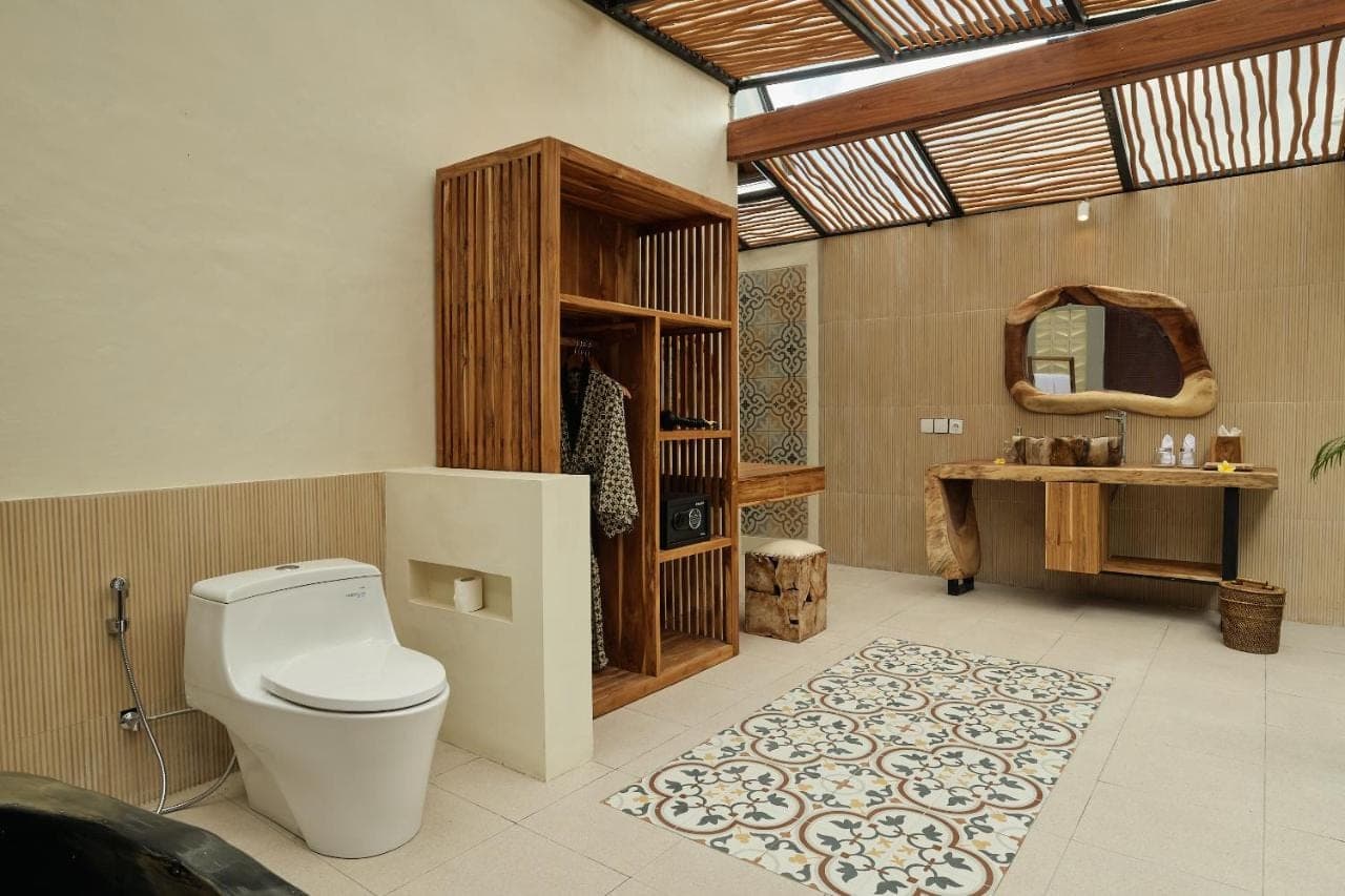 a bathroom with a toilet and a sink and a mirror at Changi Jungle Ubud Villas in Ubud