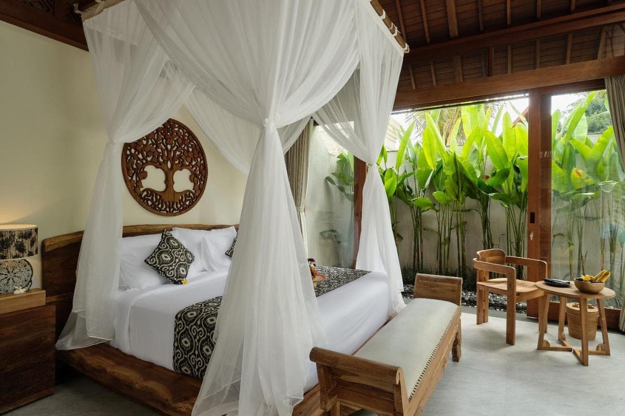 a bedroom with a bed with a canopy at Changi Jungle Ubud Villas in Ubud